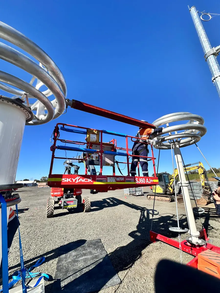 Megavar technician on an elevating work platform connecting the HV lead between the resonant reactor and the voltage divider